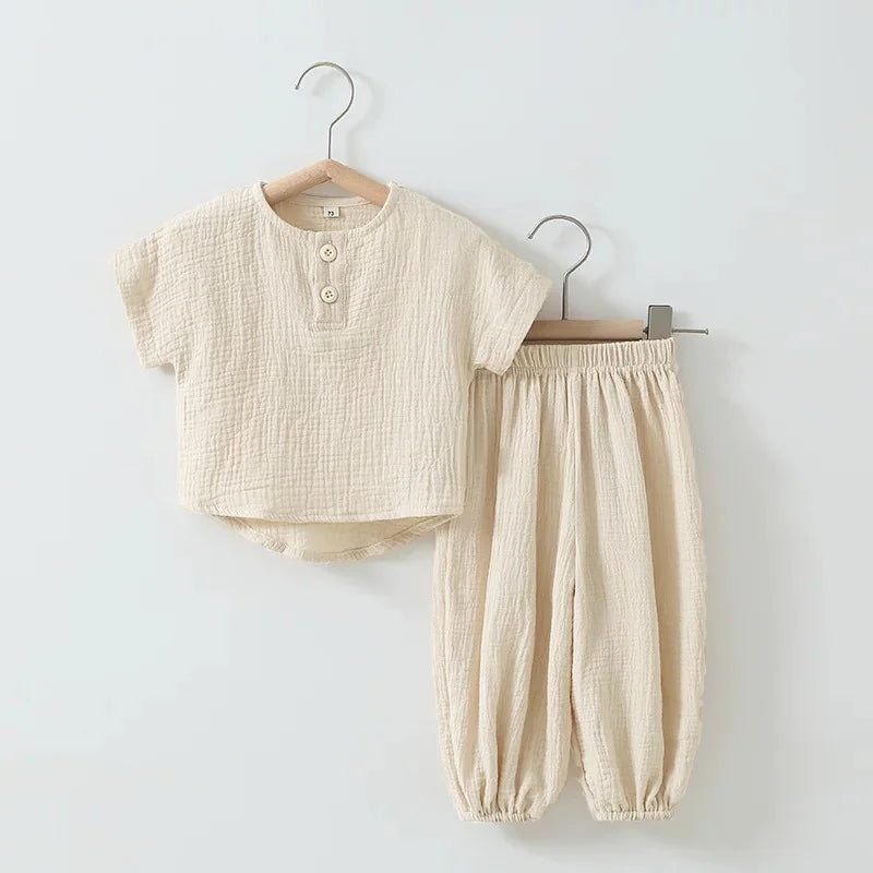 Beige baby outfit with shirt and pants on hangers against a light gray background