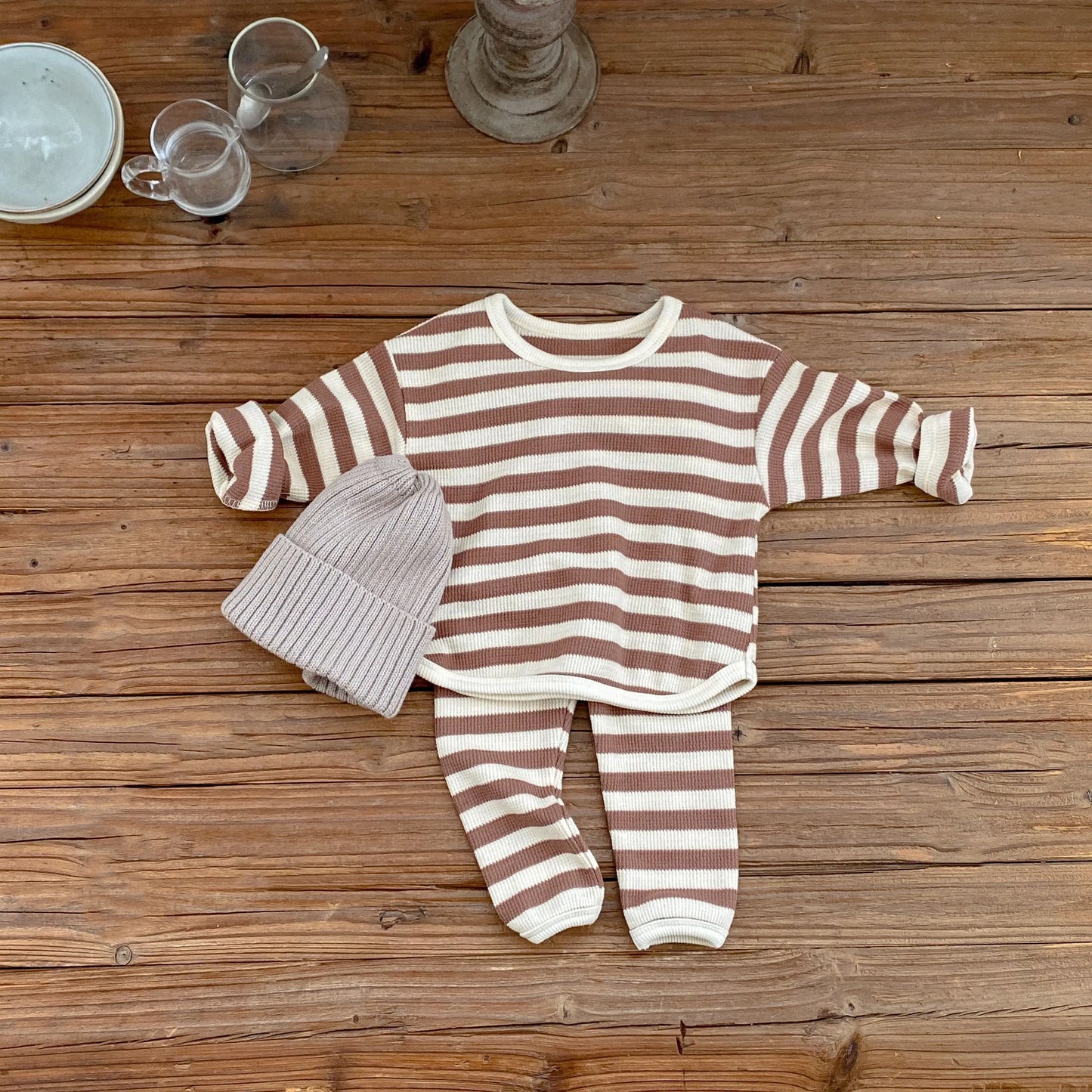 Striped baby outfit with hat on a wooden surface