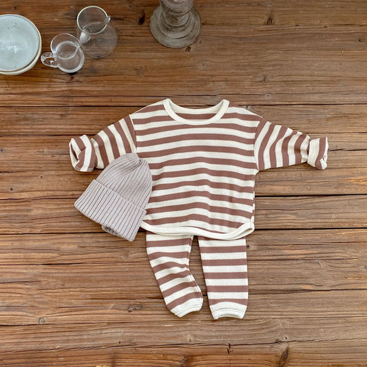 Striped baby outfit with hat on a wooden surface