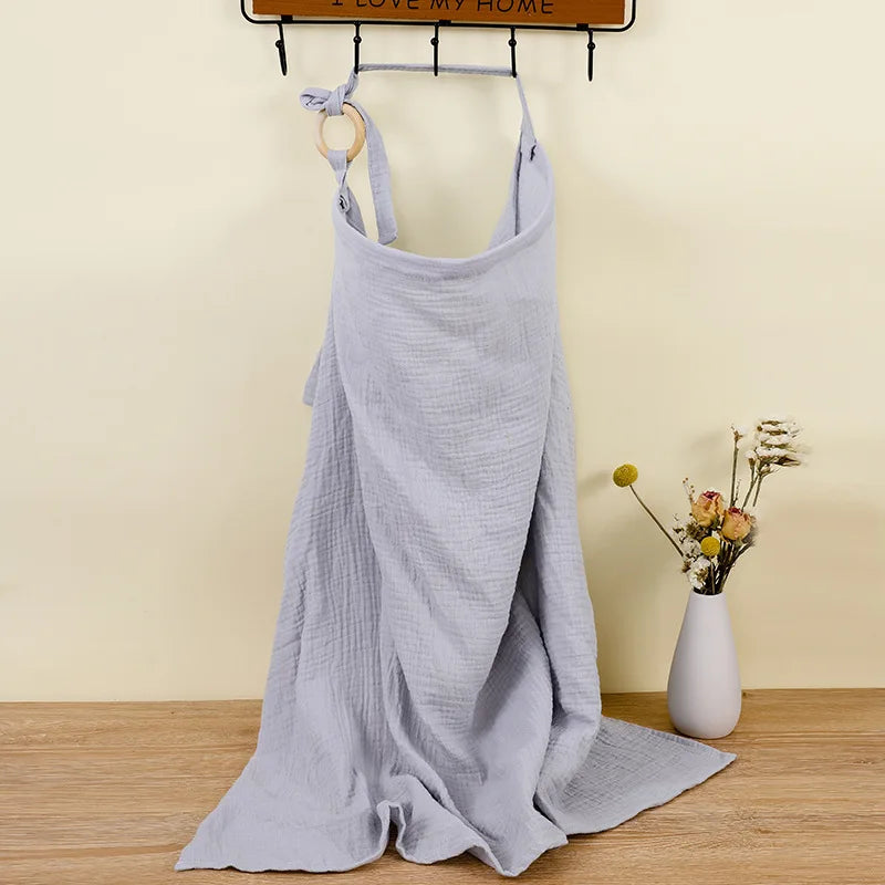 Light gray dress on a hanger against a beige wall with a vase of flowers on a wooden surface.