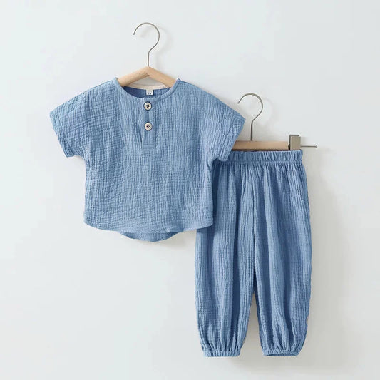 Blue children's outfit with shirt and pants on hangers against a white background