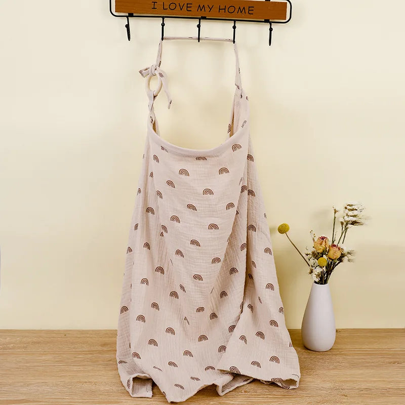 Beige apron with brown patterns on a wooden surface with a vase of flowers and a sign in the background.