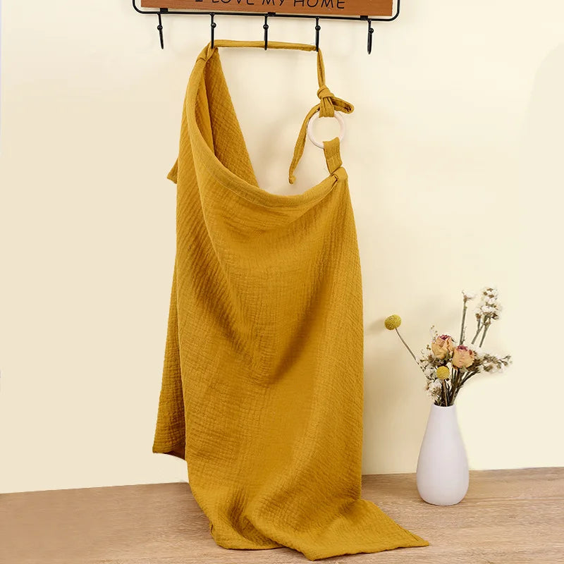 Mustard yellow dress hanging on a rack with a vase of flowers on a wooden floor.