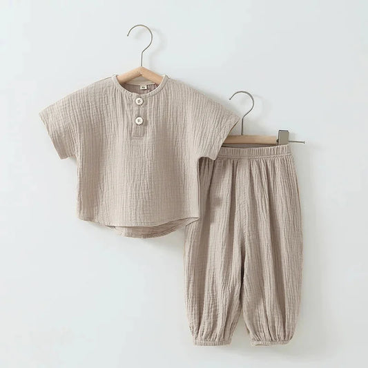 Beige children's outfit with shirt and pants on hangers against a white background